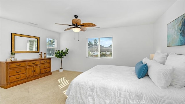 bedroom featuring a ceiling fan, visible vents, light colored carpet, and multiple windows