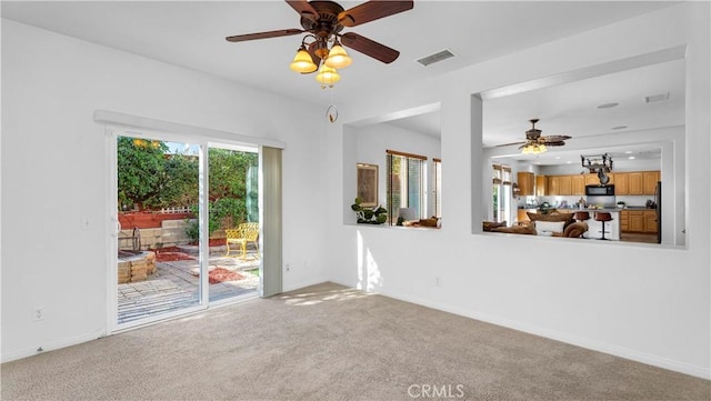 unfurnished living room with baseboards, a ceiling fan, visible vents, and carpet