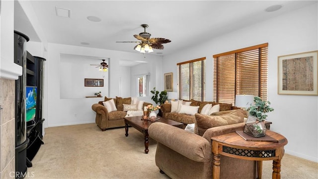living area featuring baseboards, visible vents, a ceiling fan, and light colored carpet