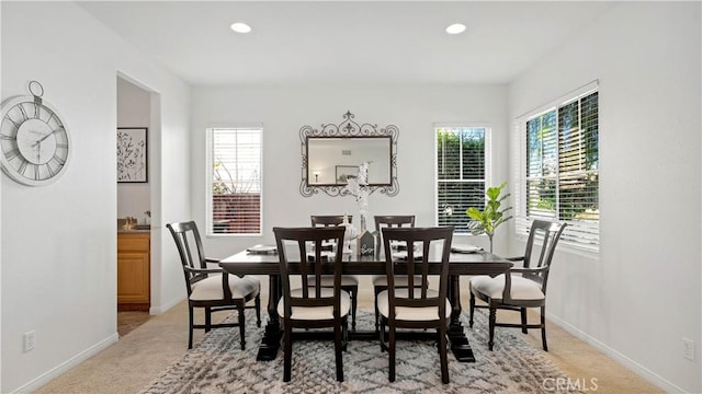 dining room featuring light carpet, a healthy amount of sunlight, and baseboards