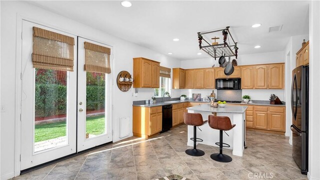 kitchen with sink, a kitchen island, a kitchen bar, and black appliances