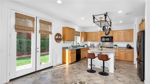 kitchen with recessed lighting, a sink, a kitchen island, black appliances, and a breakfast bar area