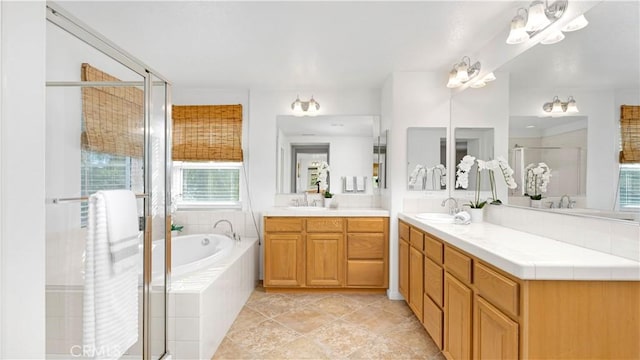 full bathroom with a bath, two vanities, a sink, and a stall shower