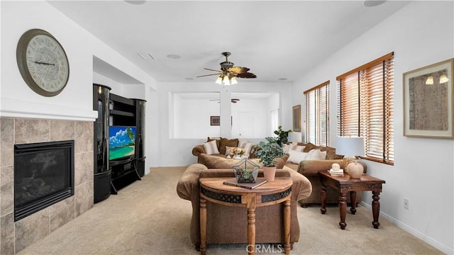 living room with baseboards, a tile fireplace, ceiling fan, and light carpet