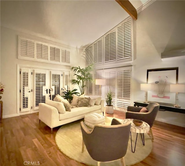 living room featuring beamed ceiling, a high ceiling, and hardwood / wood-style flooring