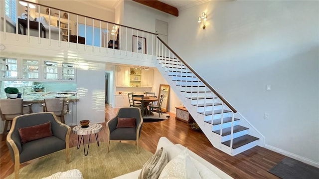 staircase featuring a towering ceiling, crown molding, sink, beam ceiling, and hardwood / wood-style flooring