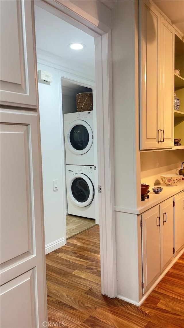 laundry room with stacked washing maching and dryer and hardwood / wood-style flooring