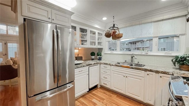 kitchen featuring light stone counters, white cabinetry, sink, and stainless steel refrigerator