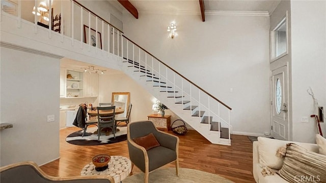 interior space with dark hardwood / wood-style floors, beam ceiling, crown molding, and a high ceiling