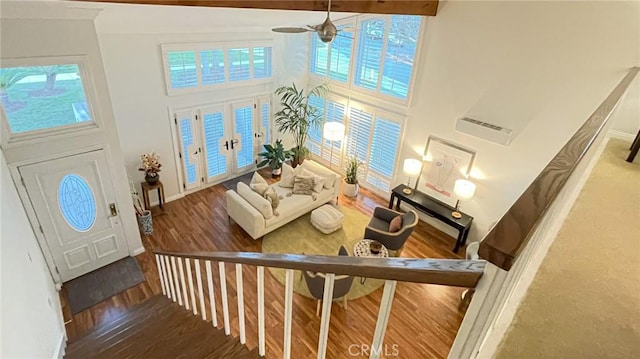 living room with ceiling fan, a towering ceiling, and wood-type flooring