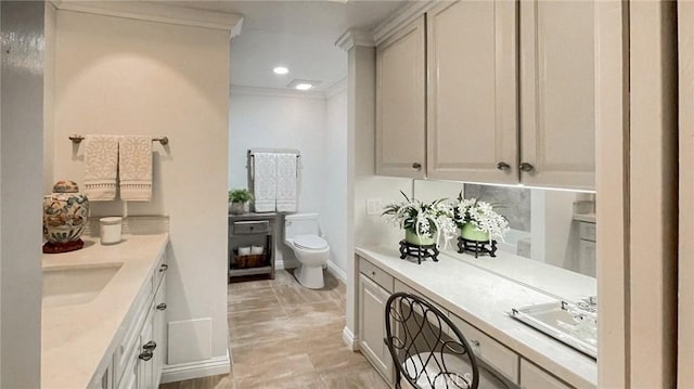 bathroom featuring toilet, vanity, and ornamental molding