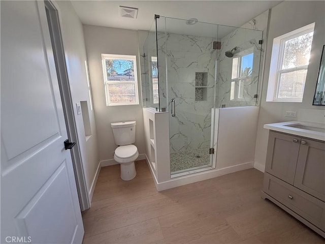 bathroom featuring vanity, hardwood / wood-style flooring, toilet, and a shower with shower door