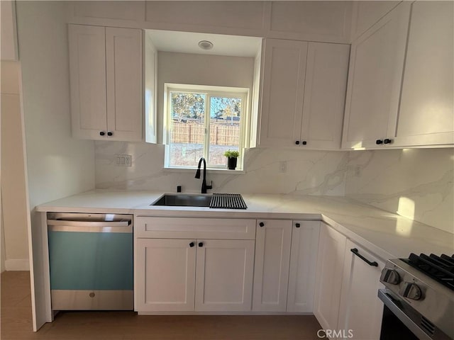 kitchen with sink, decorative backsplash, light stone countertops, white cabinetry, and stainless steel appliances