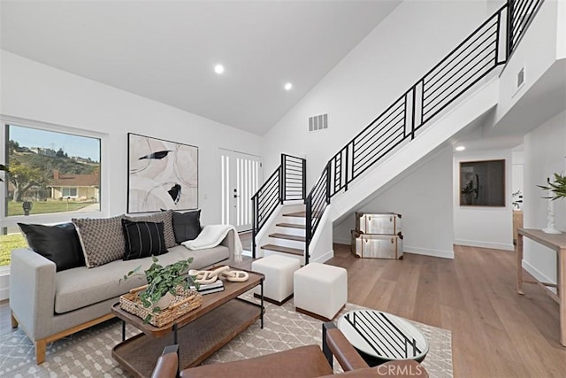 living room with high vaulted ceiling and light wood-type flooring