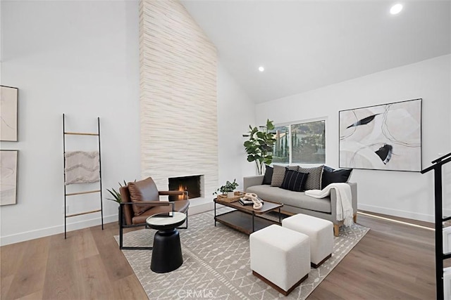 living room featuring high vaulted ceiling, hardwood / wood-style floors, and a fireplace