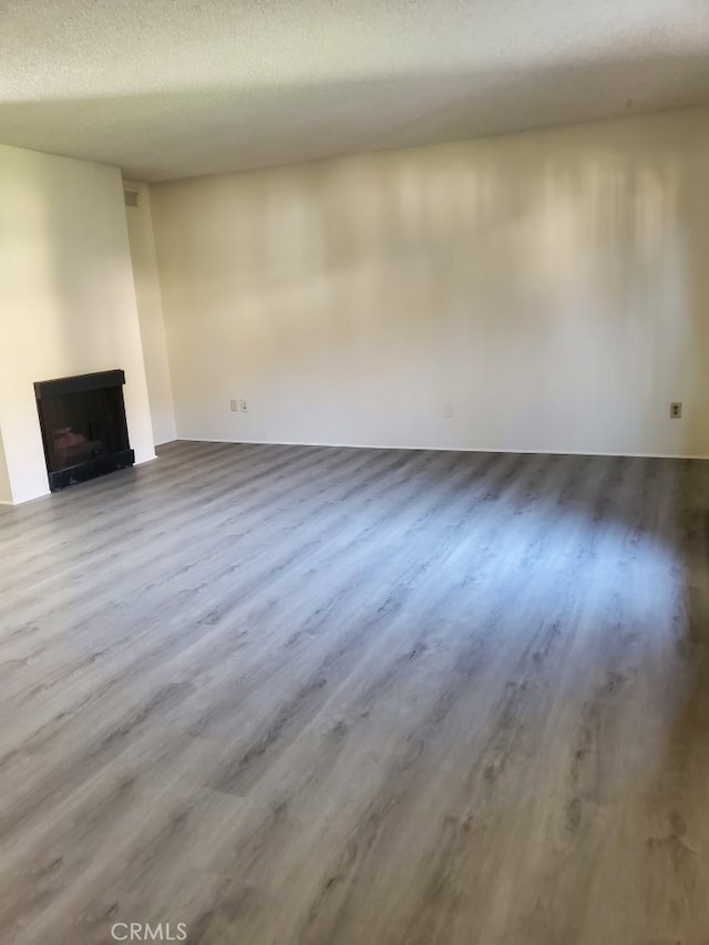 unfurnished living room featuring wood-type flooring and a textured ceiling