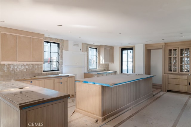 kitchen with backsplash, light brown cabinetry, and a kitchen island