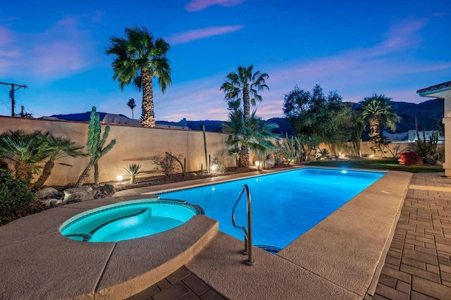 pool at dusk featuring an in ground hot tub