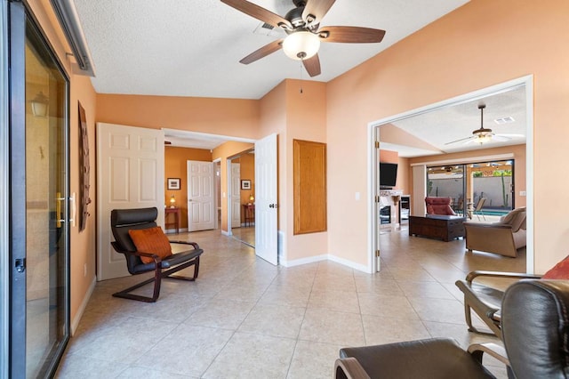 interior space featuring lofted ceiling, a textured ceiling, ceiling fan, and light tile patterned floors