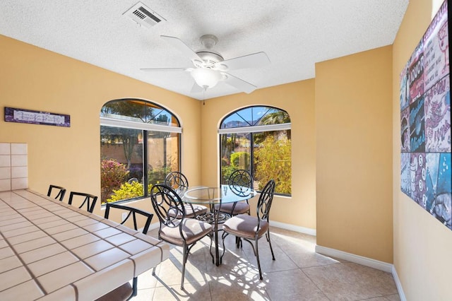 dining space with ceiling fan, a healthy amount of sunlight, light tile patterned flooring, and a textured ceiling