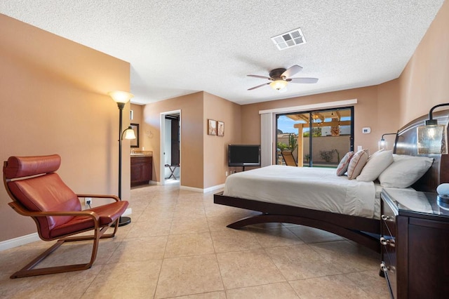 tiled bedroom featuring access to outside, ensuite bath, a textured ceiling, and ceiling fan