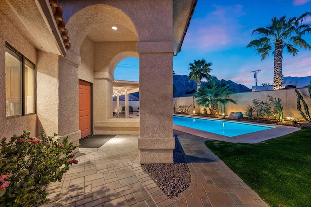 pool at dusk with a yard and a patio