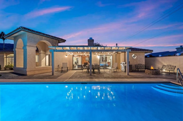 pool at dusk with a fire pit, a grill, and a patio