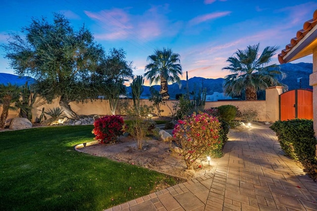 yard at dusk featuring a mountain view and a patio area