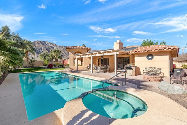 view of swimming pool featuring a mountain view, an in ground hot tub, an outdoor kitchen, and a patio area