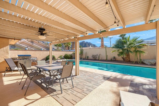 view of swimming pool featuring a patio area, an outdoor kitchen, a mountain view, area for grilling, and ceiling fan