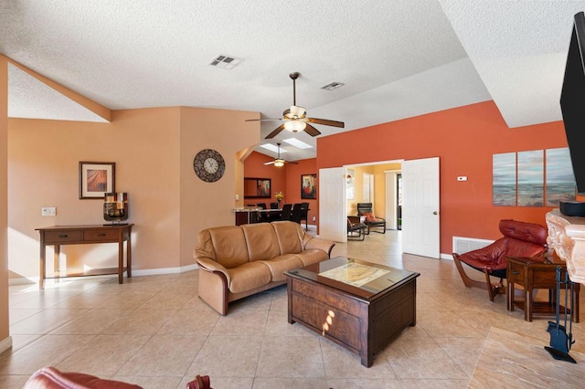 living room with ceiling fan, vaulted ceiling, a textured ceiling, and light tile patterned floors