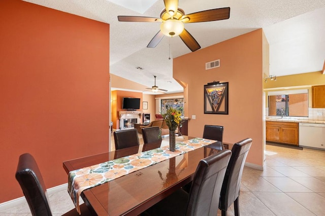 tiled dining space featuring a textured ceiling, ceiling fan, lofted ceiling, and sink