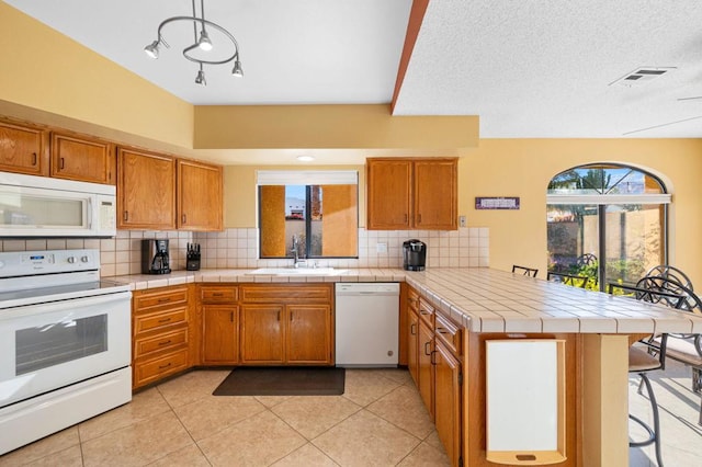 kitchen featuring white appliances, kitchen peninsula, tile countertops, tasteful backsplash, and sink