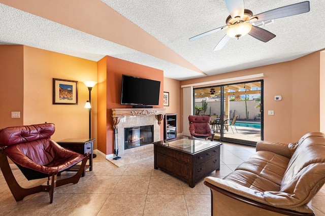 tiled living room with a textured ceiling, a fireplace, ceiling fan, and vaulted ceiling