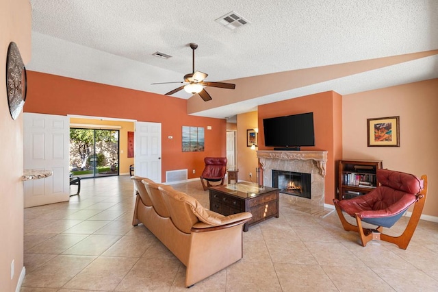 tiled living room with ceiling fan, a premium fireplace, lofted ceiling, and a textured ceiling