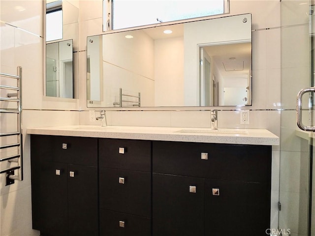 bathroom featuring walk in shower, vanity, and tile walls