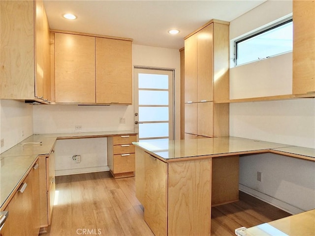 kitchen with built in desk, light hardwood / wood-style floors, and light brown cabinets