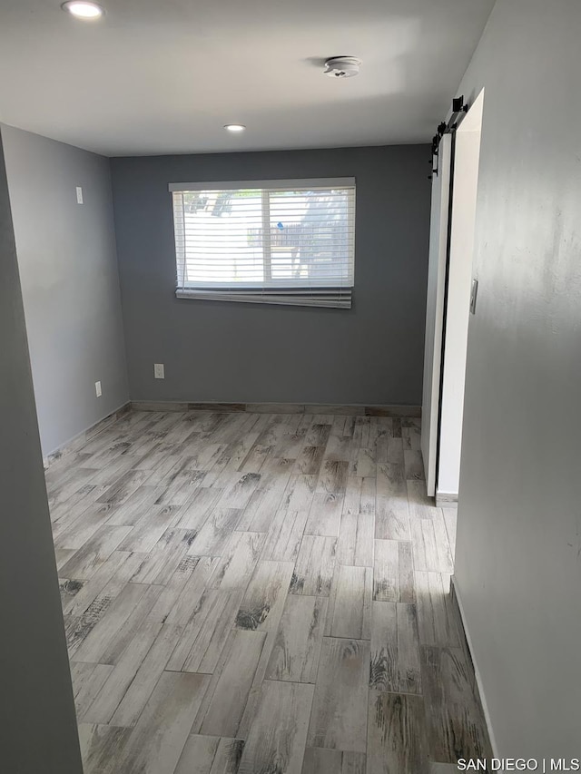 spare room featuring a barn door and light hardwood / wood-style floors