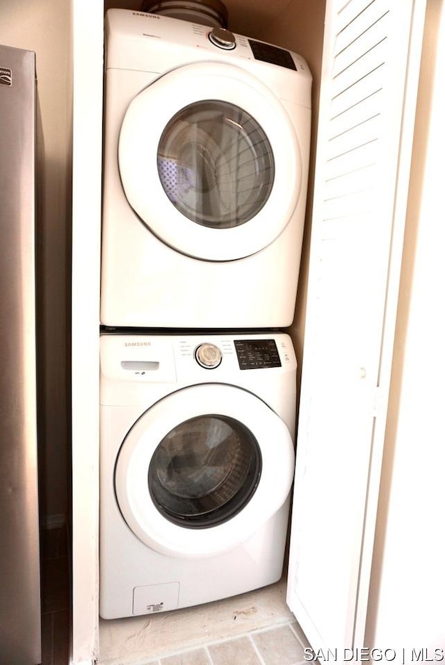 laundry area featuring stacked washer / dryer and light tile patterned floors