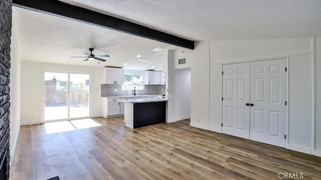 kitchen with backsplash, lofted ceiling with beams, light hardwood / wood-style floors, and white cabinets