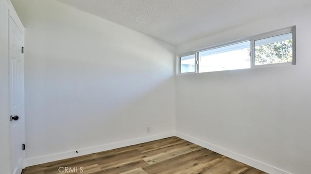 empty room with a textured ceiling and light hardwood / wood-style flooring