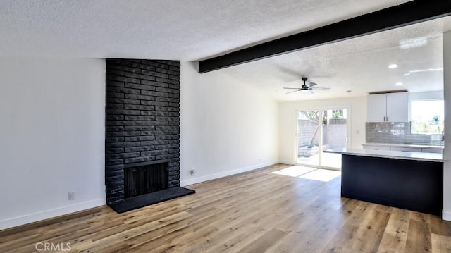 living room featuring a textured ceiling, a fireplace, and light hardwood / wood-style flooring