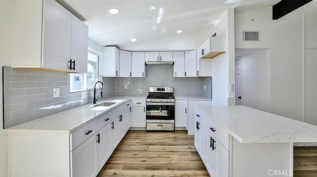 kitchen featuring white cabinetry, sink, gas range, and lofted ceiling