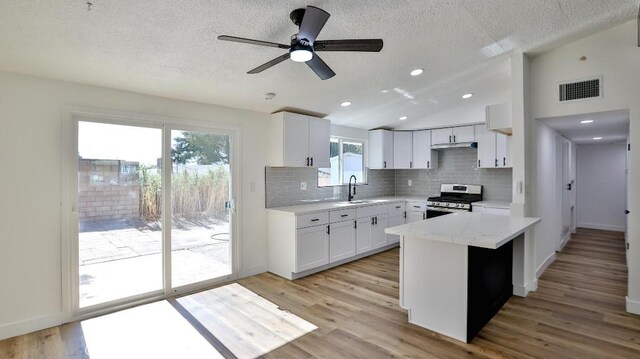 kitchen with light wood-type flooring, ceiling fan, white cabinets, stainless steel range oven, and sink