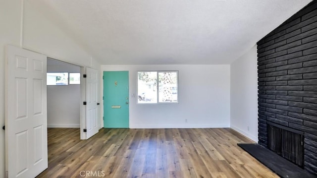 unfurnished living room with hardwood / wood-style flooring and a brick fireplace