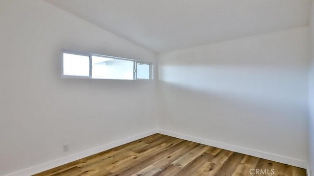 empty room with vaulted ceiling and wood-type flooring