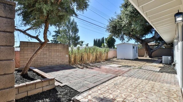 view of patio with a storage unit and central AC unit