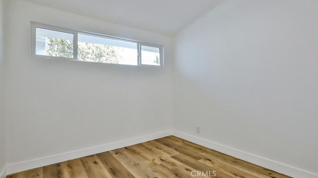 unfurnished room featuring wood-type flooring and vaulted ceiling