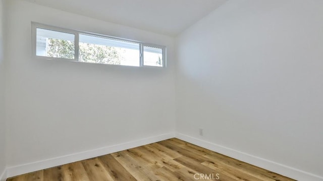 spare room with lofted ceiling and hardwood / wood-style floors