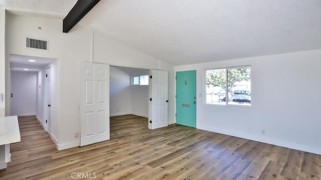 unfurnished room with hardwood / wood-style floors and lofted ceiling with beams